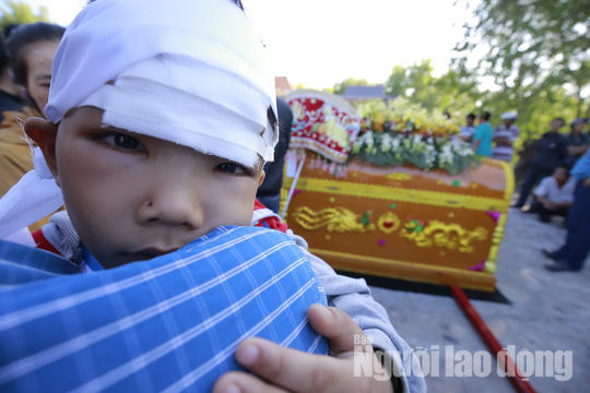 Cháu Vỹ (6 tuổi) quấn khăn tang và băng vết thương ở trán.