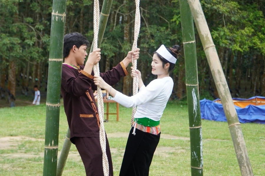 Chàng trai, cô gái Mường trong bộ trang phục truyền thống trao tình, gửi ý trong trò chơi dân gian "Đánh đu" vào dịp lễ hội.