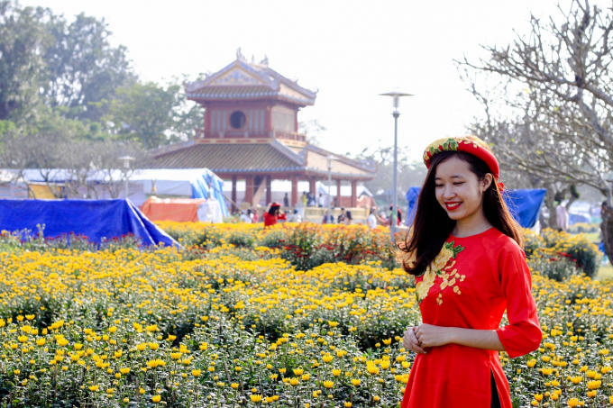 Duyên dáng trong tà áo dài bên cạnh những chậu hoa cúc rực rỡ.