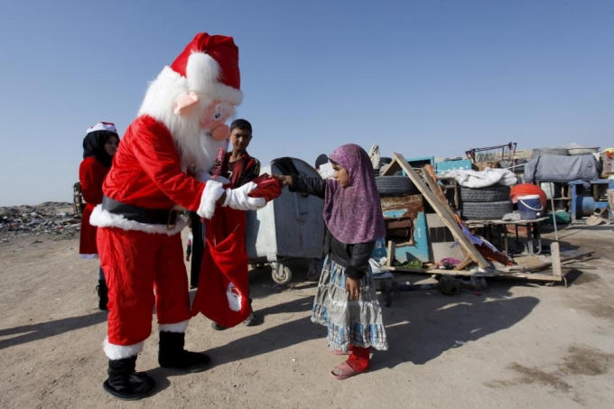 Một ông già Noel tặng quà cho những đứa trẻ ở khu dân cư nghèo tại Najaf, phía nam thủ đô Baghdad. (Ảnh: Reuters)