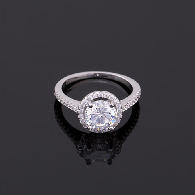 Mẫu nhẫn được tô điểm bằng một viên đá bán quý trắng lấp lánh đặt trong 1 vòng tròn đính những hạt đá nhỏ li ti vô cùng bắt mắt, xung quang thân nhẫn được trang hoàng bởi những viên đá nhỏ.