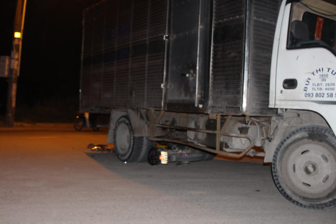 Chiếc xe máy nằm dưới gầm xe tải.