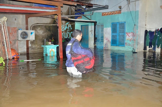 Một công nhân phải gom đồ ra ngoài vì phòng đã bị ngập sâu.