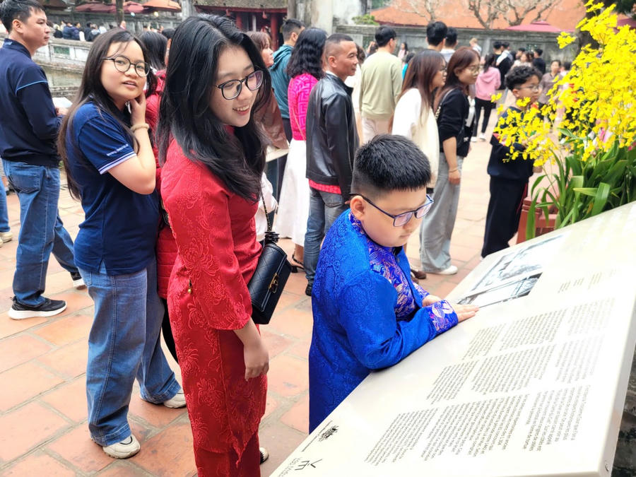 Một em nhỏ chăm chú đọc bảng giới thiệu lịch sử, tìm hiểu về truyền thống hiếu học tại trường đại học đầu tiên của Việt Nam. (Ảnh: Phạm Duy)
