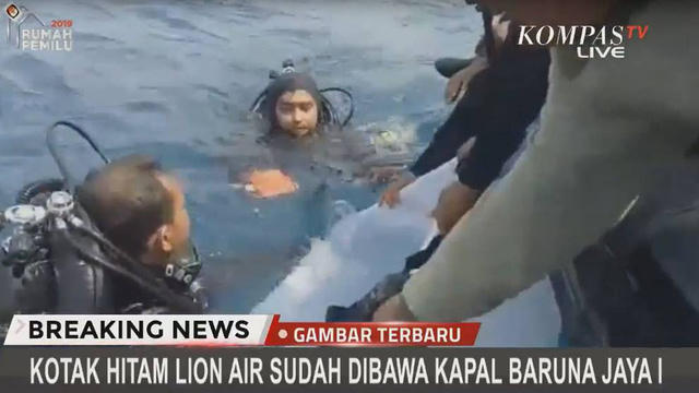 Ảnh chụp màn hình bản tin của Kompas TV cho thấy một thợ lặn chuyển hộp đen tìm thấy dưới đáy biển lên tàu. (Ảnh: CNA)