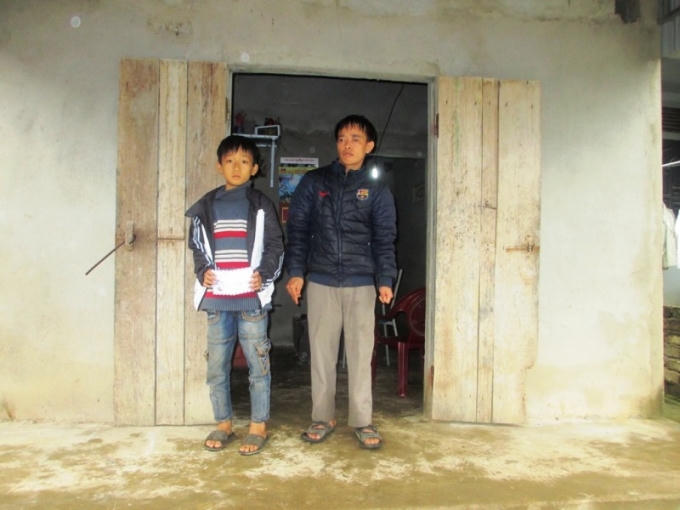 Hai cha con anh Dương trước căn nhà được chính quyền địa phương và anh em làm cho.