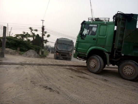 Những chiếc xe tải trọng lớn nối đuôi nhau ra vào bến cảng.