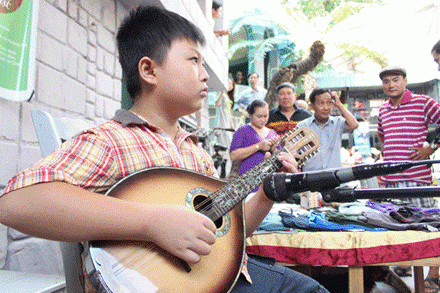 Cậu bé chơi thử “ngay và luôn” cây đàn măngđôlin vừa… mới sắm.
