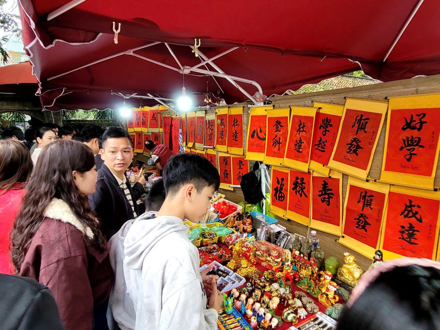 Các gian hàng thư pháp, quà lưu niệm rực rỡ sắc đỏ thu hút sự quan tâm lớn của các bạn trẻ muốn tìm "lộc" chữ đầu năm. (Ảnh: Phạm Duy)