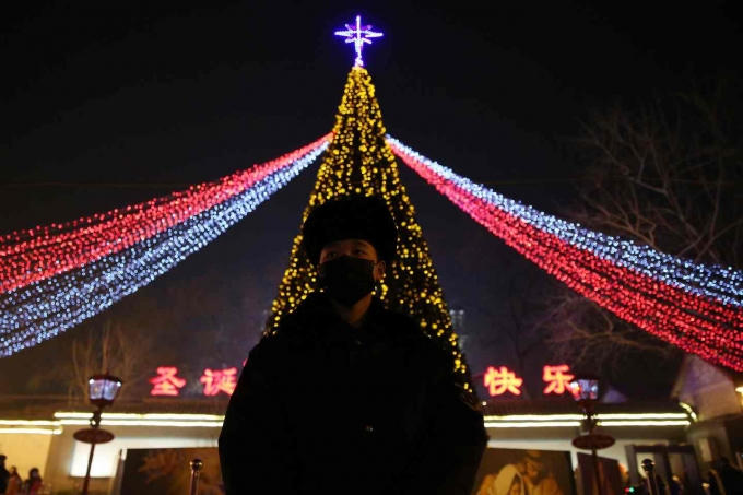 Một nh&acirc;n vi&ecirc;n cảnh s&aacute;t bịt k&iacute;n khẩu trang trong đ&ecirc;m hội Gi&aacute;ng sinh tại Bắc Kinh, Trung Quốc. (Ảnh: Ng&ocirc; Hồng / EPA)