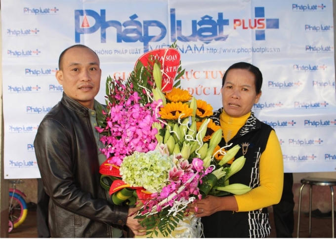 Bà Nguyễn Thị Mai vợ ông Hàn Đức Long rất xúc động khi nhận hoa chúc mừng từ đại diện Tòa soạn Pháp luật Plus.