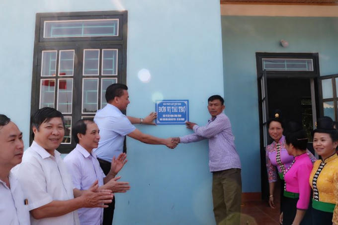 Ông Vũ Đình Tiến- Trưởng Văn phòng đại diện báo Pháp Luật Việt Nam khu vực phía Bắc (trong cùng bên trái) trao biển bàn giao Nhà văn hóa cho đại diện xã Nà Nhạn (huyện Điện Biên).