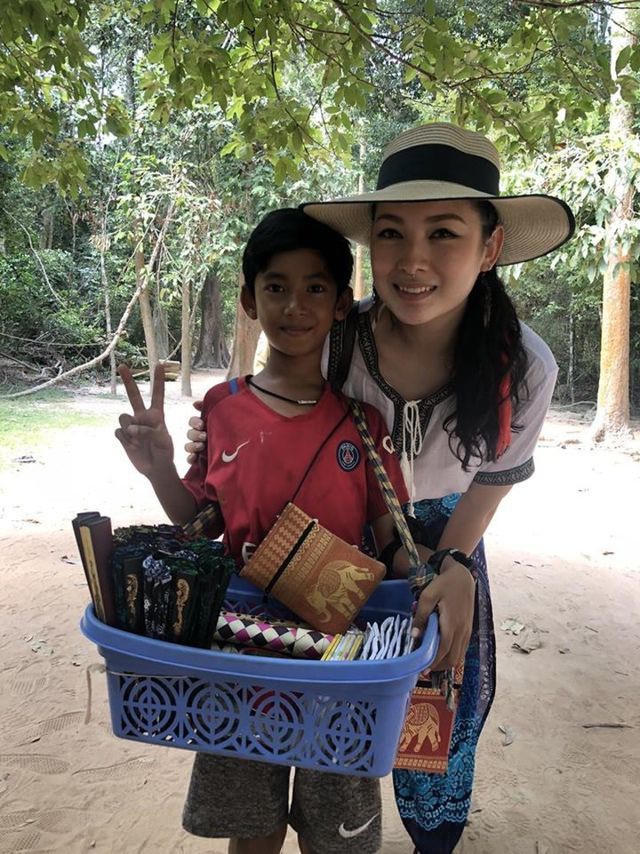 Cậu bé bán hàng rong người Campuchia chụp ảnh cùng khách du lịch