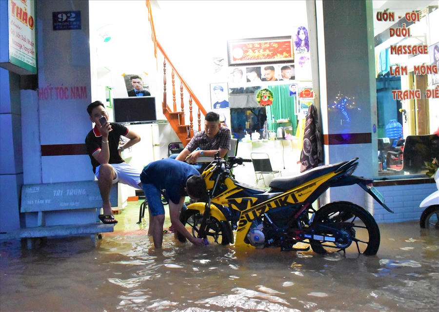 Nước tràn vào nhà. Người dân vô tư bấm điện thoại và rửa xe. Ảnh: Thành