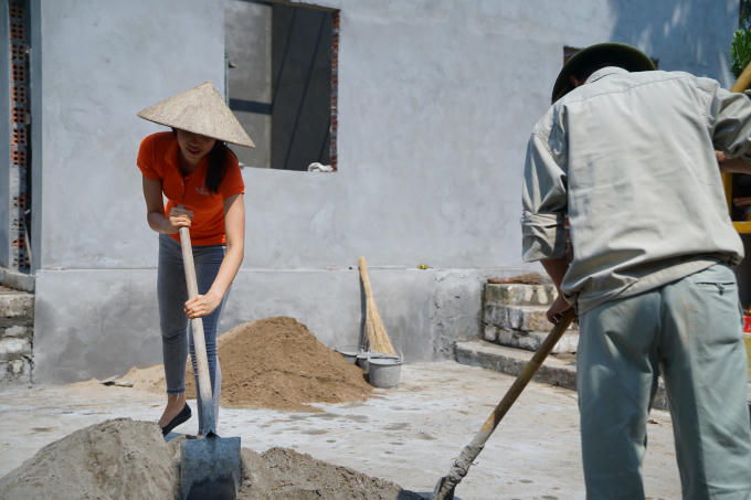 Phạm Hương đội nón, cầm xẻng đi xúc cát.