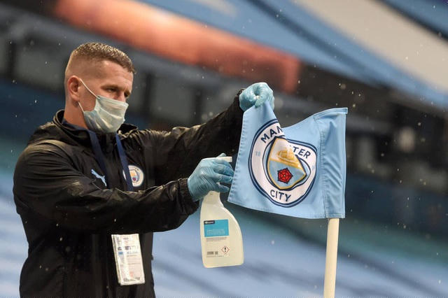 Một nhân viên của Man City khử trùng lá cờ ở điểm góc sân trước khi trận đấu diễn ra, công tác phòng chống đại dịch Covid-19 được các đội bóng tuân thủ nghiêm ngặt