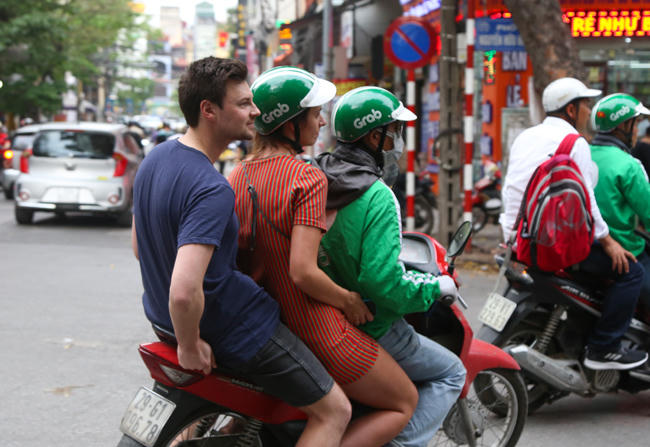 Kể cả khi khách hàng là du khách nước ngoài, các tài xế GrabBike cũng không ngần ngại kẹp 3 thiếu mũ.