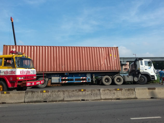 Chiếc xe container nằm nghiêng có nguy cơ lật xuống hầm công trình.