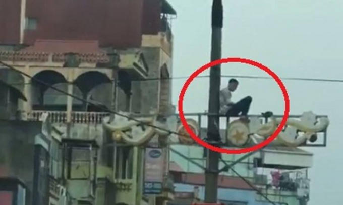 Nam thanh niên ngồi cố thủ trên cây cột điện.