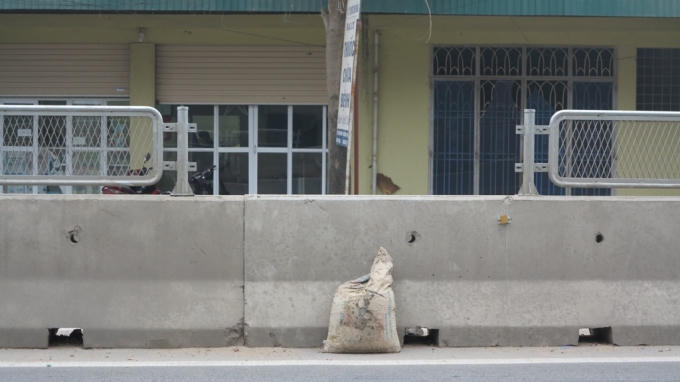 Một bao tải đất được đặt nơi vị trí tấm lan can đã tháo dỡ để người dân tiện "vượt rào".