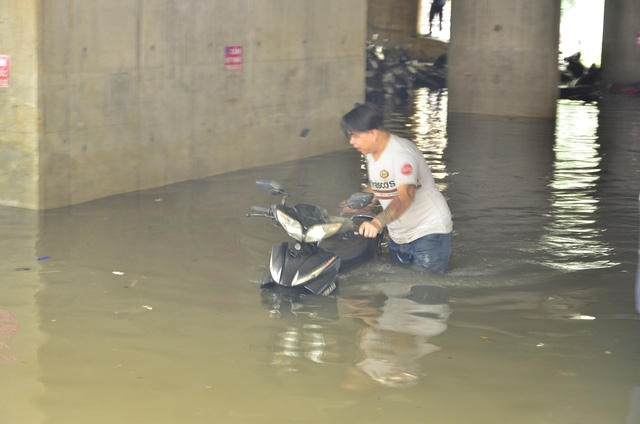 Nhân viên bãi xe dầm mình dưới nước bẩn, tìm và dắt xe ra cho khách.