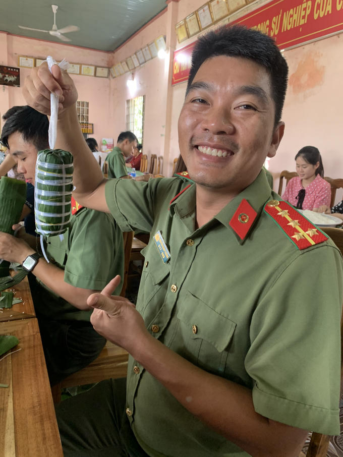 Một chiến sĩ công an miệng khoe chiếc bánh đượm nghĩa tình mà mình vừa gói xong