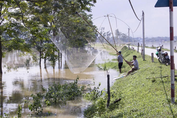 Người d&acirc;n tranh thủ d&ugrave;ng v&oacute; k&eacute;o c&aacute; ngay ven đường b&ecirc; t&ocirc;ng.
