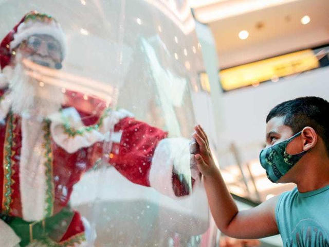 Brasilia, Brazil: Ông già Noel ở trong quả cầu tuyết chào đón các em nhỏ, thay vì tiếp xúc gần với các em nhỏ như những năm trước.