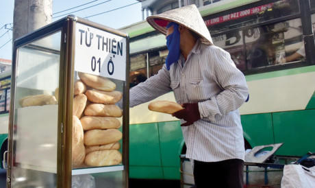 Một người mua ve chai đang lấy bánh mì từ thiện.