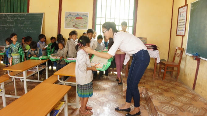 Diệu Ngọc trao cặp sách cho các em học sinh tiểu học.