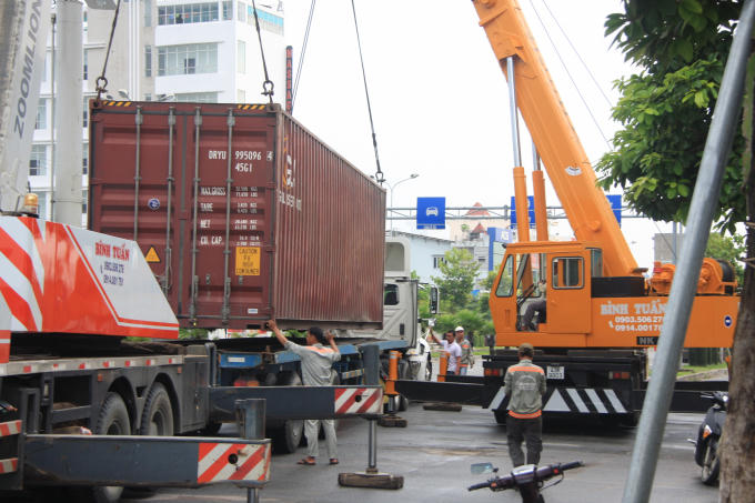 Cơ quan chức năng nâng container lên xe sau vụ tai nạn giao thông.