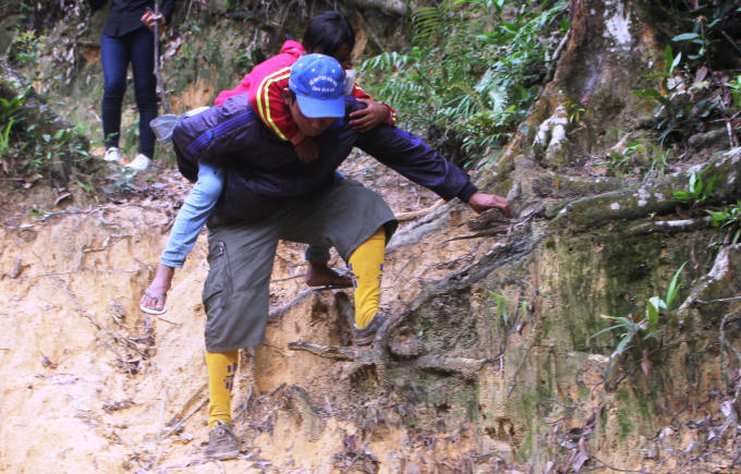 Vừa cõng các em, các thầy cô còn huấn luyện và chỉ bảo các em cách vượt qua đường lầy lội và dốc để đến trường an toàn.