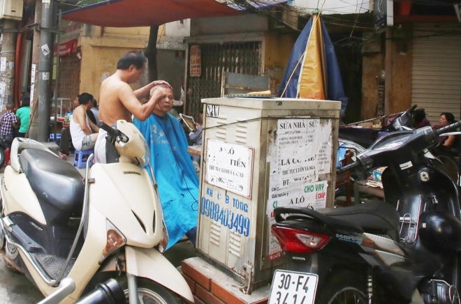Cắt tóc vỉa hè bên cạnh bốt điện phố Hàng Vải (Hoàn Kiếm).