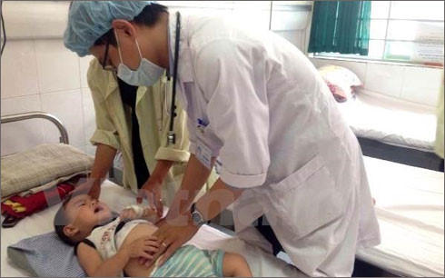 Bác sỹ của Bệnh viện Nhi Trung ương khám cho trẻ bị bệnh viêm não. Ảnh: Vietnamplus