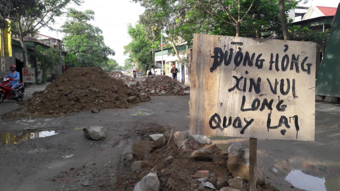 Một tấm biển lớn với dòng chữ "Đường hỏng xin vui lòng quay lại" được cắm ở đầu tuyến đường để báo hiệu cho tài xế.