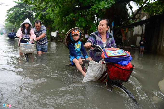 7h sáng là thời gian nhiều học sinh phải tới trường. Bà Ngô Thị Kiều Hạnh và cháu Huỳnh Duy Khang dắt bộ xe đạp trên đường An Dương Vương, quận 6, cho biết: "Ngày nào cũng đưa cháu đi học mà gặp trời mưa thì chỉ biết lội đến trường".