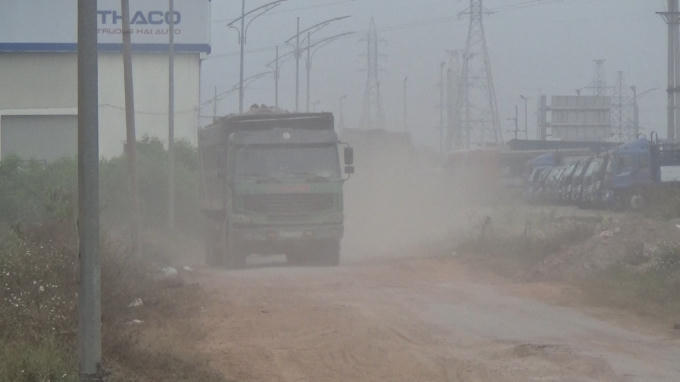Đường bụi mù, xe trọng tải lợn chạy trên đường gom.