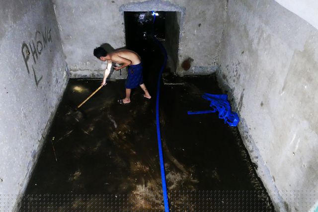 Nước được hút cạn, lộ ra lớp dầu thải nhầy nhụa dưới sàn hầm bề chứa.