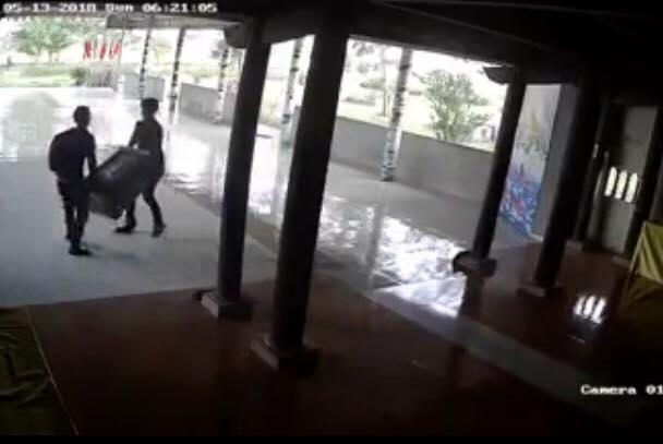 Hình ảnh hai tên trộm rinh chiếc hòm công đức ra ngoài được camera ghi lại (ảnh cắt từ clip).
