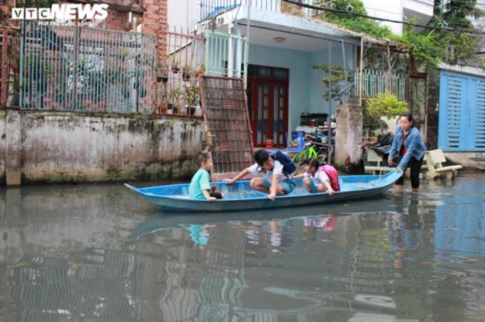 Thay vì dùng xe máy, những ngày triều cường lên, người dân sống trong con hẻm này phải dùng xuồng đưa con đi học.