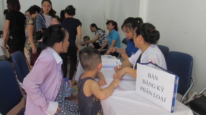 Trẻ được gia đình đưa đến uống Vitamin A cũng như cân được các y tá của Trạm y tế phường hướng dẫn đăng ký và phân loại độ tuổi trẻ. (Ảnh: Thu Hường)