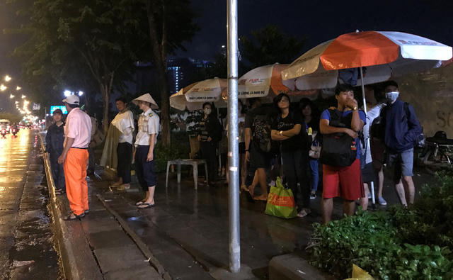Người đi đường co ro trong thời tiết mưa gió đón xe để trở về nhà trên đại lộ Mai Chí Thọ, quận 2, TPHCM trong tối 4/6.