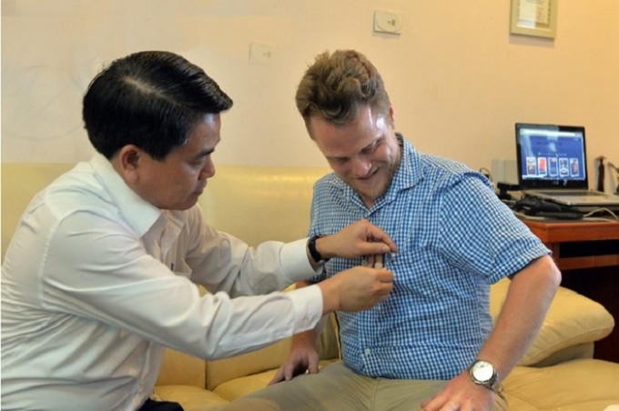 Chủ tịch Nguyễn Đức Chung (bìa trái) đã tặng và gắn lên ngực áo anh James Joseph Kendall logo của thành phố Hà Nội.