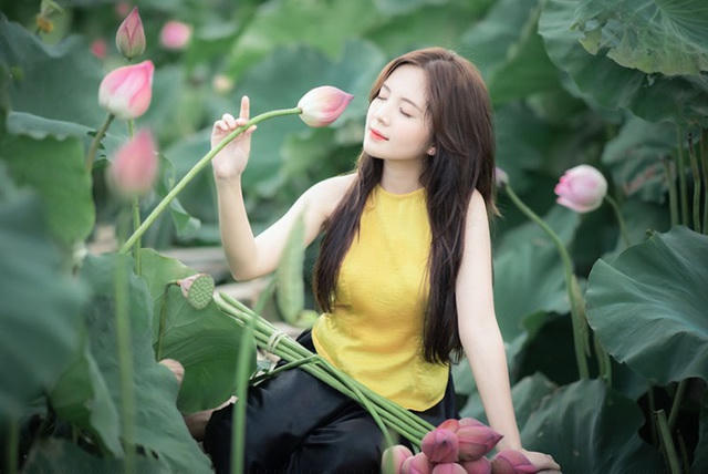 Cô thoải mái, tự tin tạo dáng bên hoa sen buổi nắng mai.