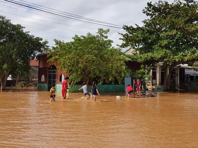 Các em nhỏ vui chơi trên con đường ngập nước.