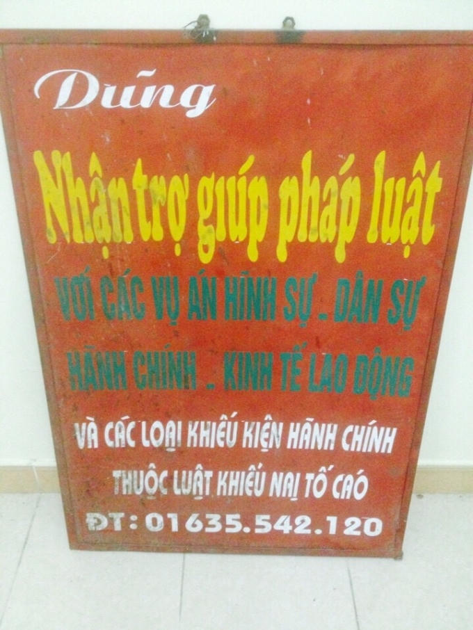 Dũng trưng tấm biển quảng cáo nhận trợ giúp pháp lý đặt trước cửa hàng bán thịt lợn.