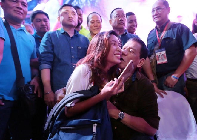 Ông Duterte hôn má một người phụ nữ trong buổi vận động tranh cử tổng thống. (Ảnh:Inquirer)