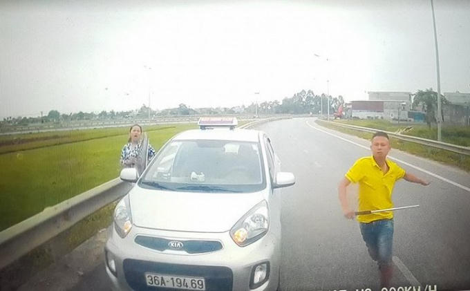 Không được nhường đường, thanh niên này còn mở cửa xe và rút tuýp sắt đòi xử tài xế. (Ảnh: cắt từ clip)