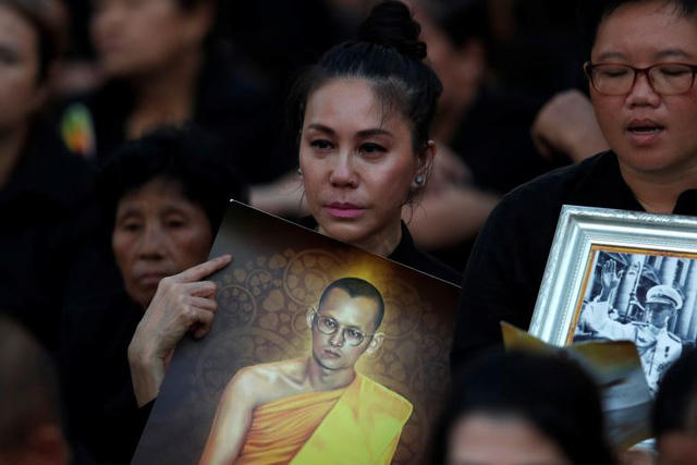 Quốc vương Bhumibol Adulyadej băng hà ngày 13/10/2016 ở tuổi 88 sau một thời gian lâm bệnh nặng. Trong suốt 7 thập niên trị vì, Quốc vương được người dân yêu mến vì tài năng và đức độ, giúp Thái Lan ổn định chính trị và phát triển kinh tế mạnh mẽ như ngày nay. Trong ảnh: Người Thái mang di ảnh Quốc vương Bhumibol Adulyadej đứng chờ trước Đài hóa thân hoàng gia khi lễ hỏa táng chuẩn bị bắt đầu.