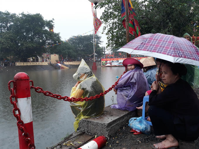 Nhiều người trung tuổi bất chấp trời mưa to vẫn đứng, ngồi dọc 2 bên khúc sông hồi hộp xem và cổ vũ cuộc thi truyền thống của làng 5 năm mới tổ chức một lần.